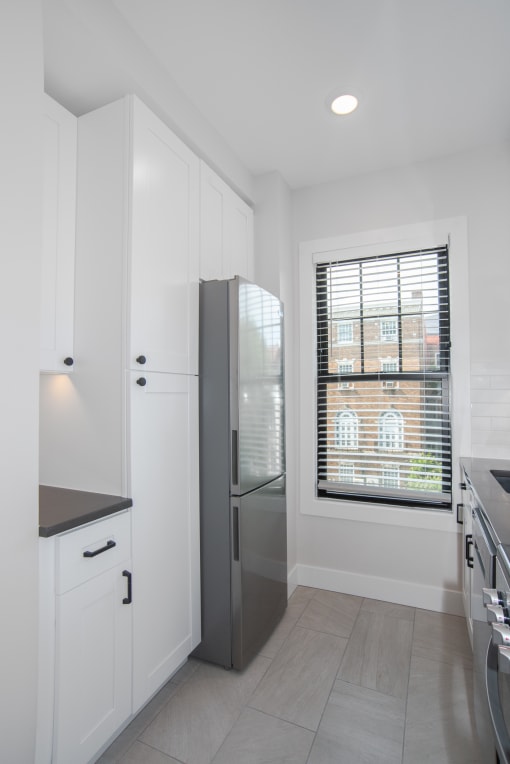 a kitchen with white cabinets and a stainless steel refrigerator