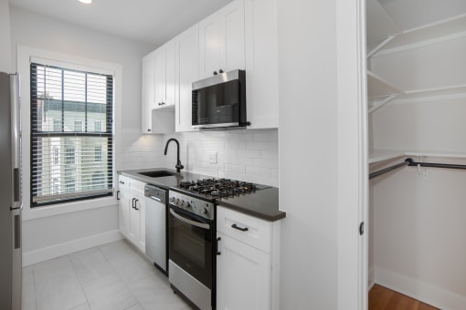 a kitchen with white cabinets and a stove and a microwave