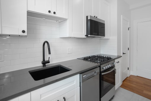 a kitchen with white cabinets and a sink and a stove