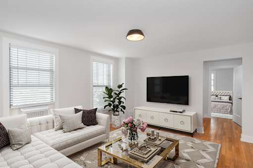 A living room with a white couch, a coffee table, and a flat screen TV.