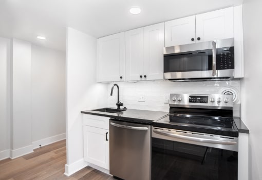 a kitchen with white cabinets and a stove and a microwave