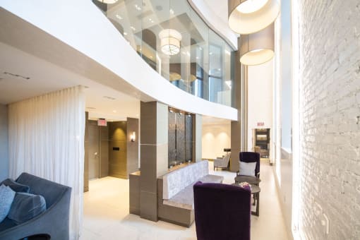 the lobby of a building with purple chairs and a reception desk