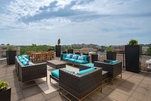 A patio with wicker furniture and blue cushions.