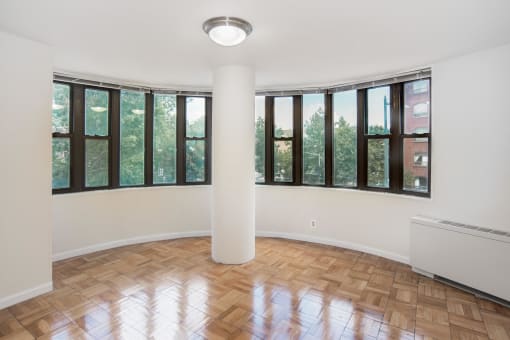 an empty living room with windows and wood flooring