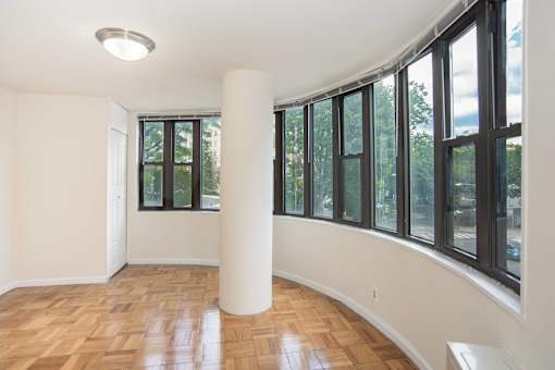 an empty living room with large windows and wood flooring