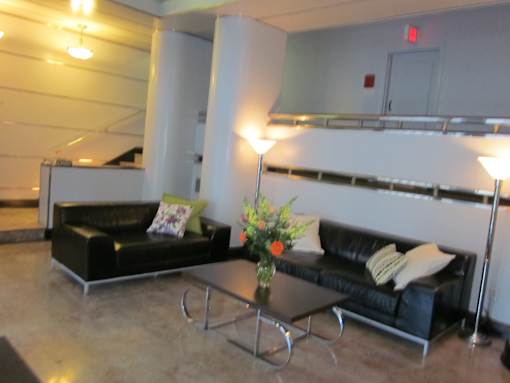A black couch with a yellow pillow is in front of a white wall.