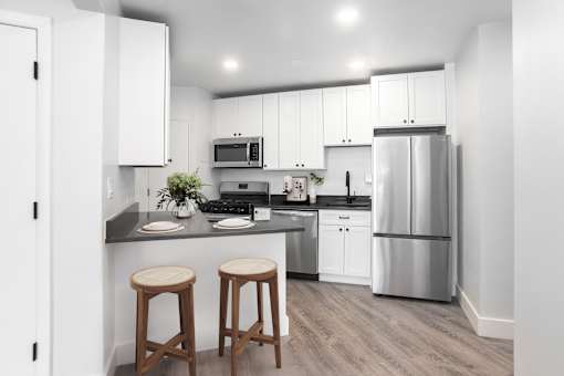 A kitchen with white cabinets and a grey floor.