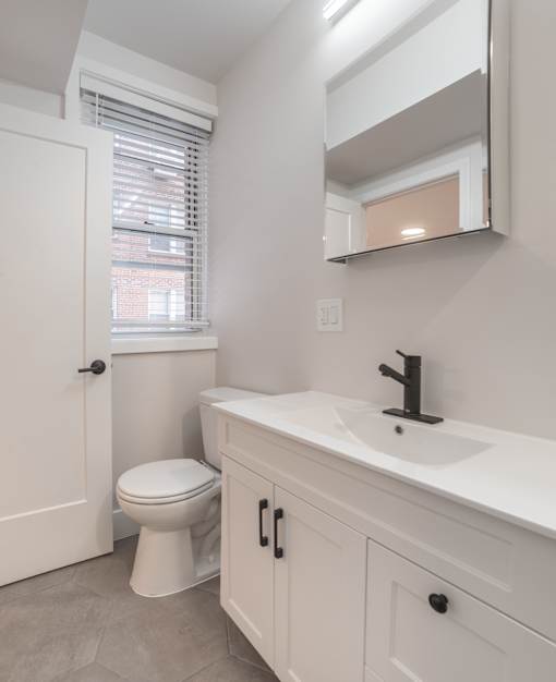 A white bathroom with a toilet, sink, and mirror.
