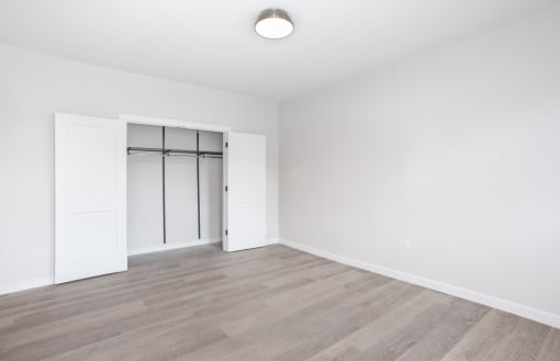 an empty living room with white walls and wood flooring and a white closet with