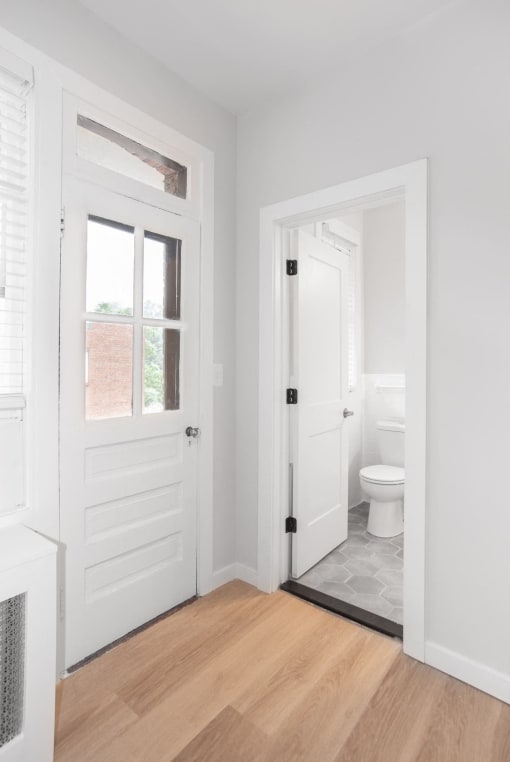 a white bathroom with a white door and a white toilet
