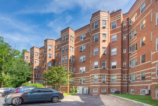 a large red brick apartment building with cars parked outside
