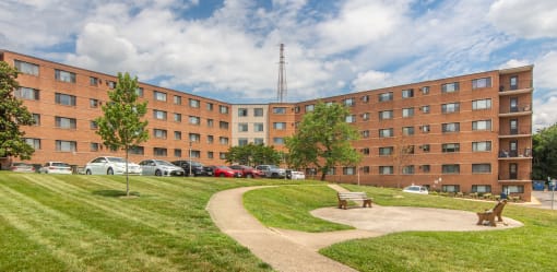a large brick building with a park in front of it