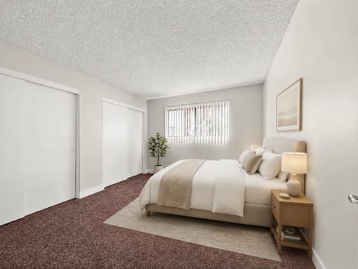 A bedroom with a bed, nightstand, and window.