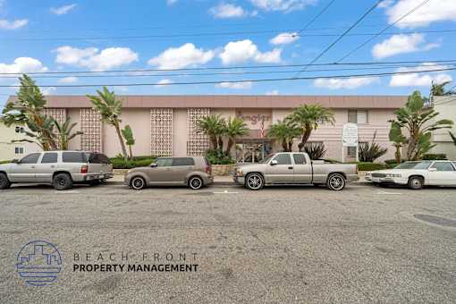 A parking lot with several cars and a building in the background with the words Beach Front Property Management.