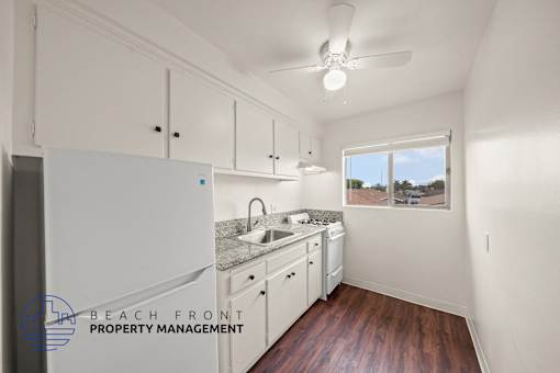 A kitchen with white cabinets and a window overlooking the beach.