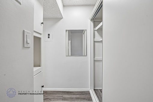 A white hallway with a door on the left and a window on the right.