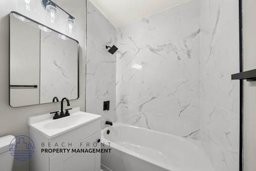 A bathroom with a marble wall and a white sink.