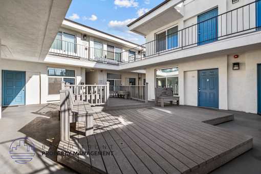 A balcony with a table and chairs is on the second floor of a building.