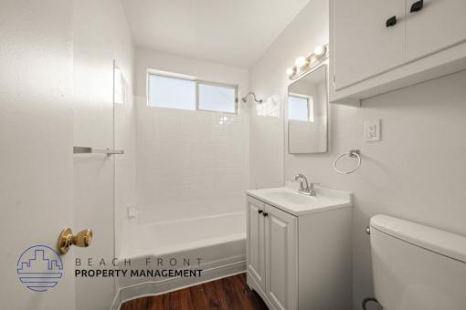 A white bathroom with a sink, mirror, and tub.