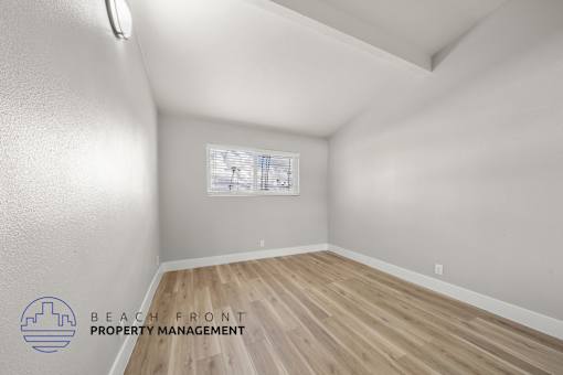A room with wooden flooring and a window with blinds.