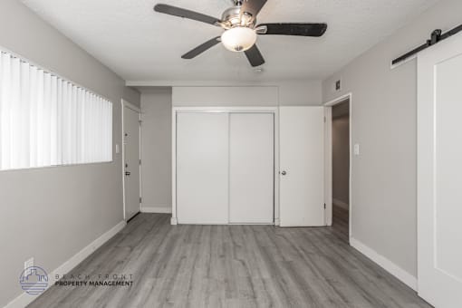 A room with a ceiling fan and sliding doors.