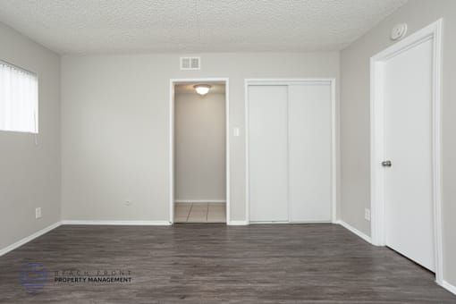 A room with a white door and a window with white blinds.