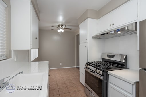 A kitchen with a stove top oven and a fan ceiling light.
