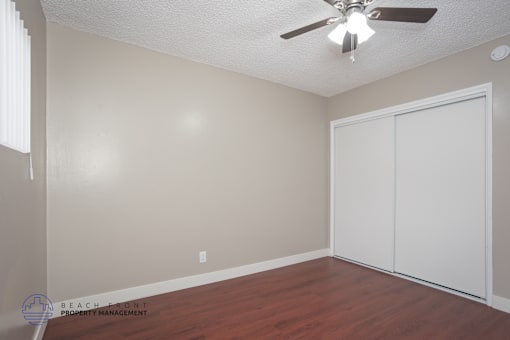 A room with a ceiling fan and a white closet door.