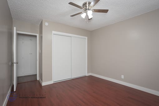 A room with a ceiling fan and a door leading to another room.