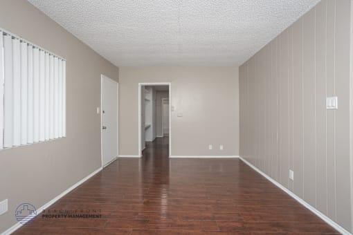 A spacious room with wooden floors and white walls.