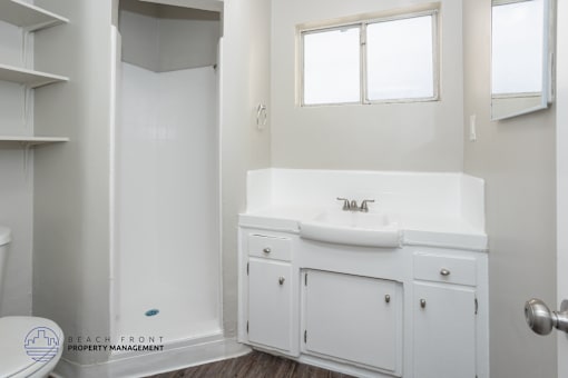 A white bathroom with a toilet, sink, and cabinet.