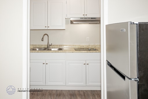 A kitchen with white cabinets and a stainless steel refrigerator.
