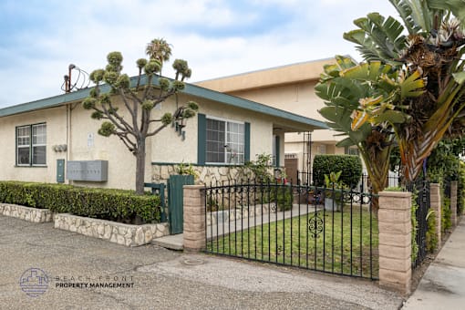 A house with a green fence and a tree in front.