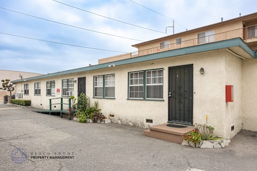 A building with a red door and a sign that says Beach Front Property Management.