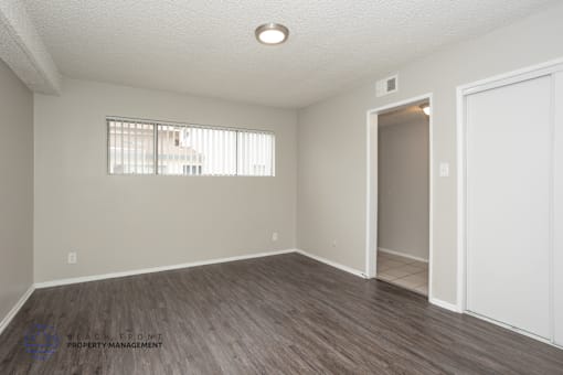 A room with a wooden floor and a window with blinds.
