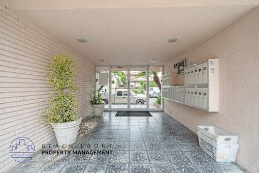 A hallway with a plant and a sign for Beach Front Property Management.