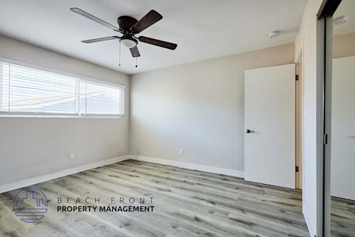 A room with a ceiling fan and wooden flooring.