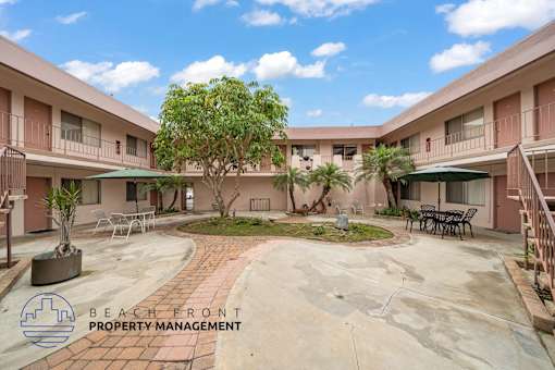 A courtyard with a tree in the middle and apartment buildings surrounding it.