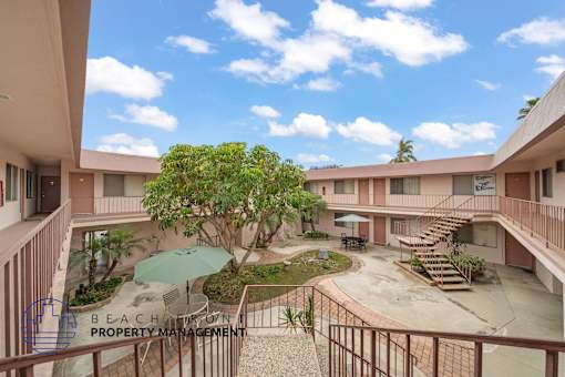 A courtyard with a tree and a table surrounded by buildings.