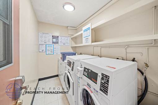 A laundry room with washers and dryers and a sign that says Beach Front Property Management.