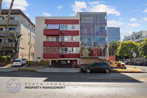 A modern building with a red and white facade is managed by Beach Front Property Management.