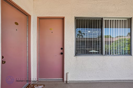 A pink door and window with a view of trees outside.