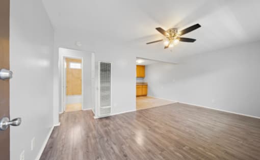 A room with a ceiling fan and wooden flooring.