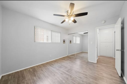 A room with a ceiling fan and wooden flooring.