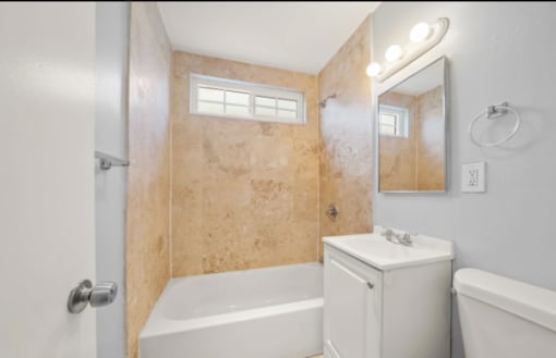 A bathroom with a white tub, sink, and toilet.