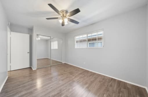 A room with a ceiling fan and wooden flooring.