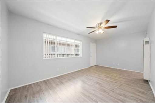 A room with a ceiling fan and a window with blinds.