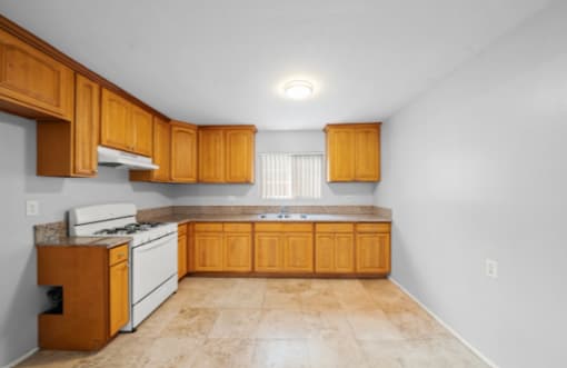 A kitchen with wooden cabinets and a white stove top oven.