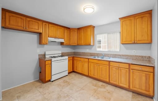 A kitchen with wooden cabinets and a white stove top oven.