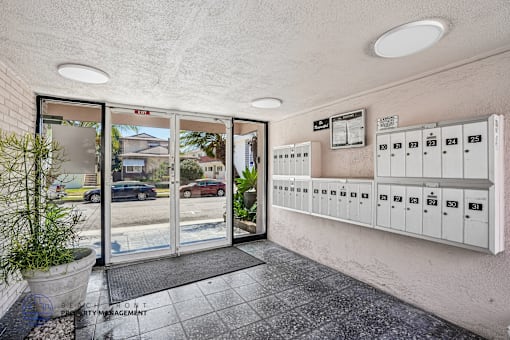 A view of a parking garage with a glass door and a wall of mailboxes.